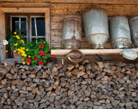Milchkannen an Hauswand über Holz